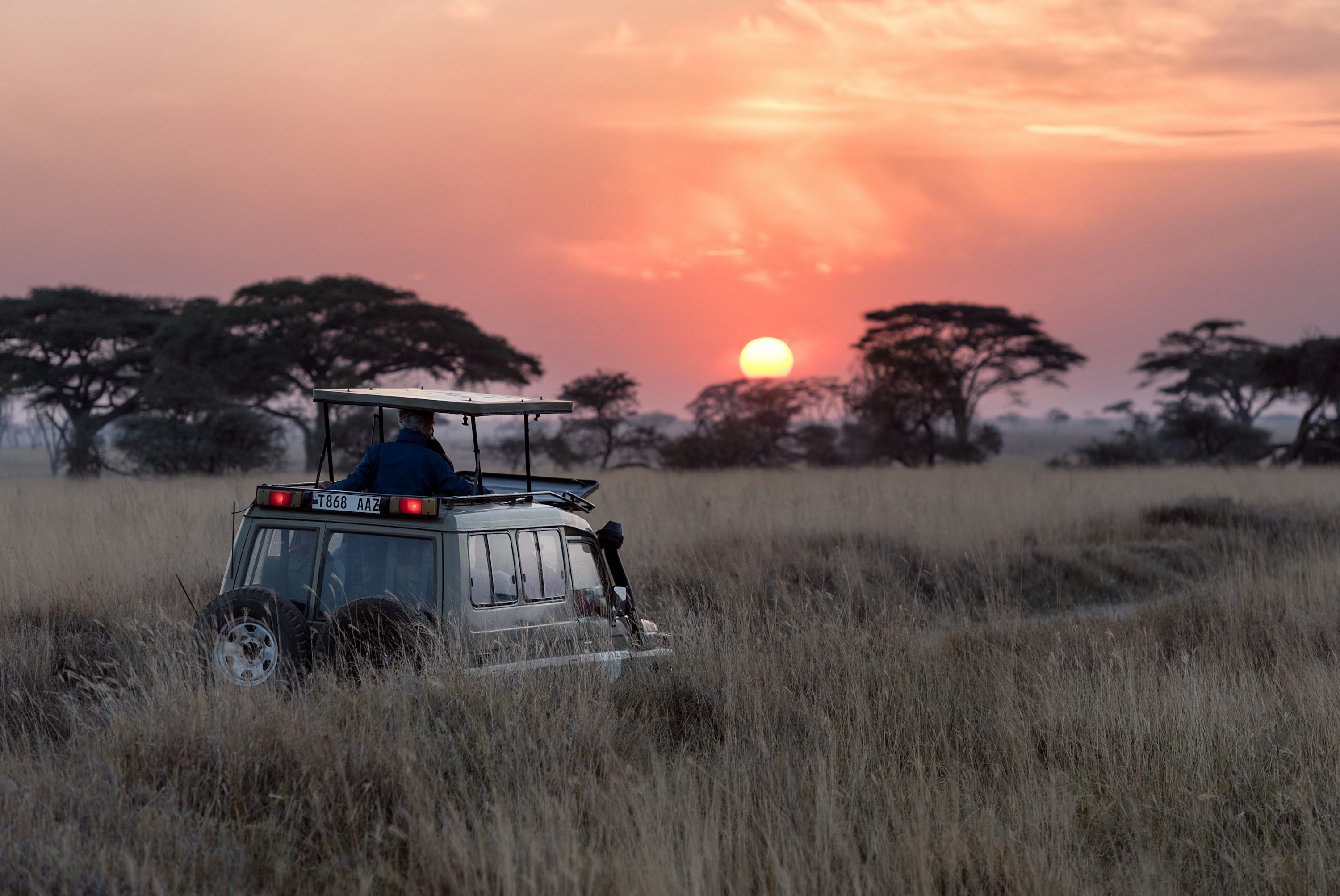 Luxury African safari vehicle parked on the savanna at sunset, symbolizing a private journey.