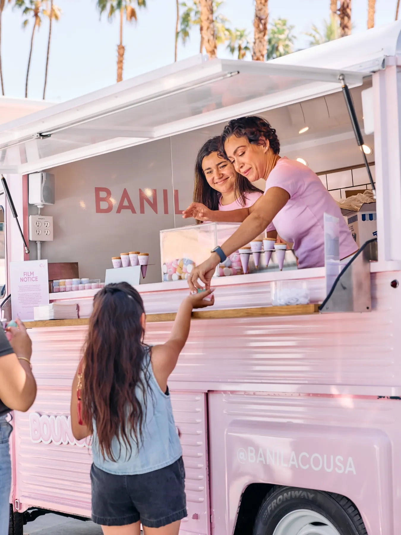 Banila Co ambassadors handing a skincare sample to a guest from a Retro Roll Citroën HY mobile sampling van. 