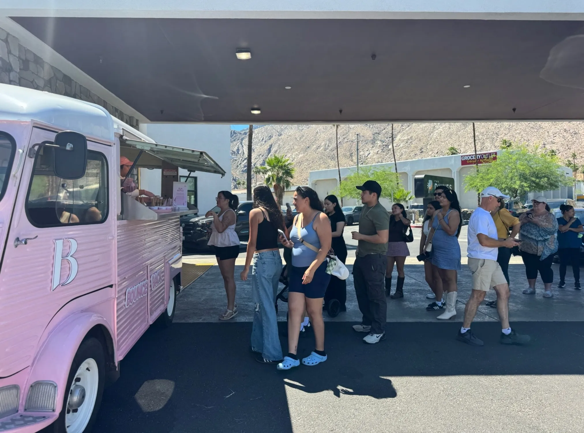 Festivalgoers lined up at a Banila Co Citroën HY sampling van near a Palm Springs Coachella shuttle location. 