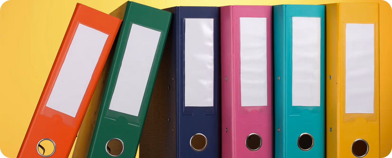 Six colorful office binders in red, green, blue, pink, teal, and yellow arranged upright against a yellow background.