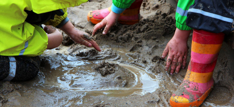 Bild på barn i gummistövlar som leker i en sandlåda