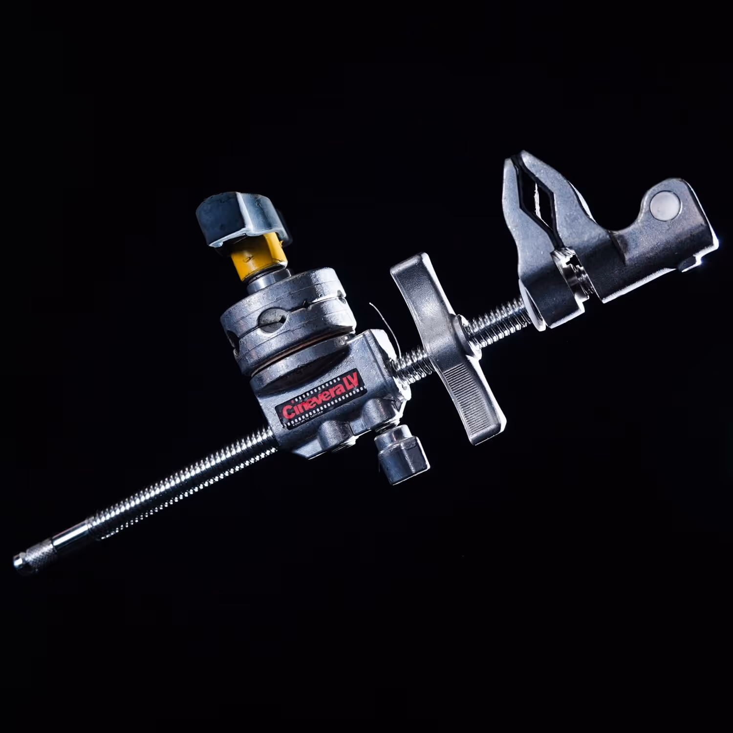 Close-up of a silver Cinevera LV clamp with a black and yellow adjustment knob on a black background.