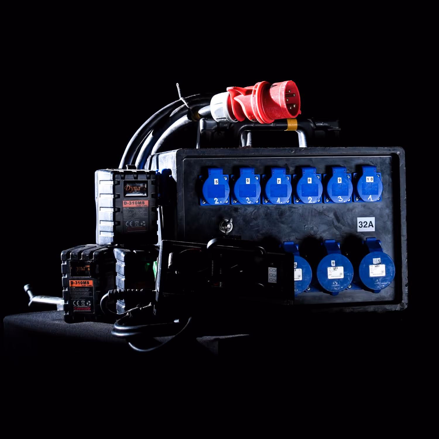 Black power distribution box with multiple blue outlets, connected cables, and a red plug on top.