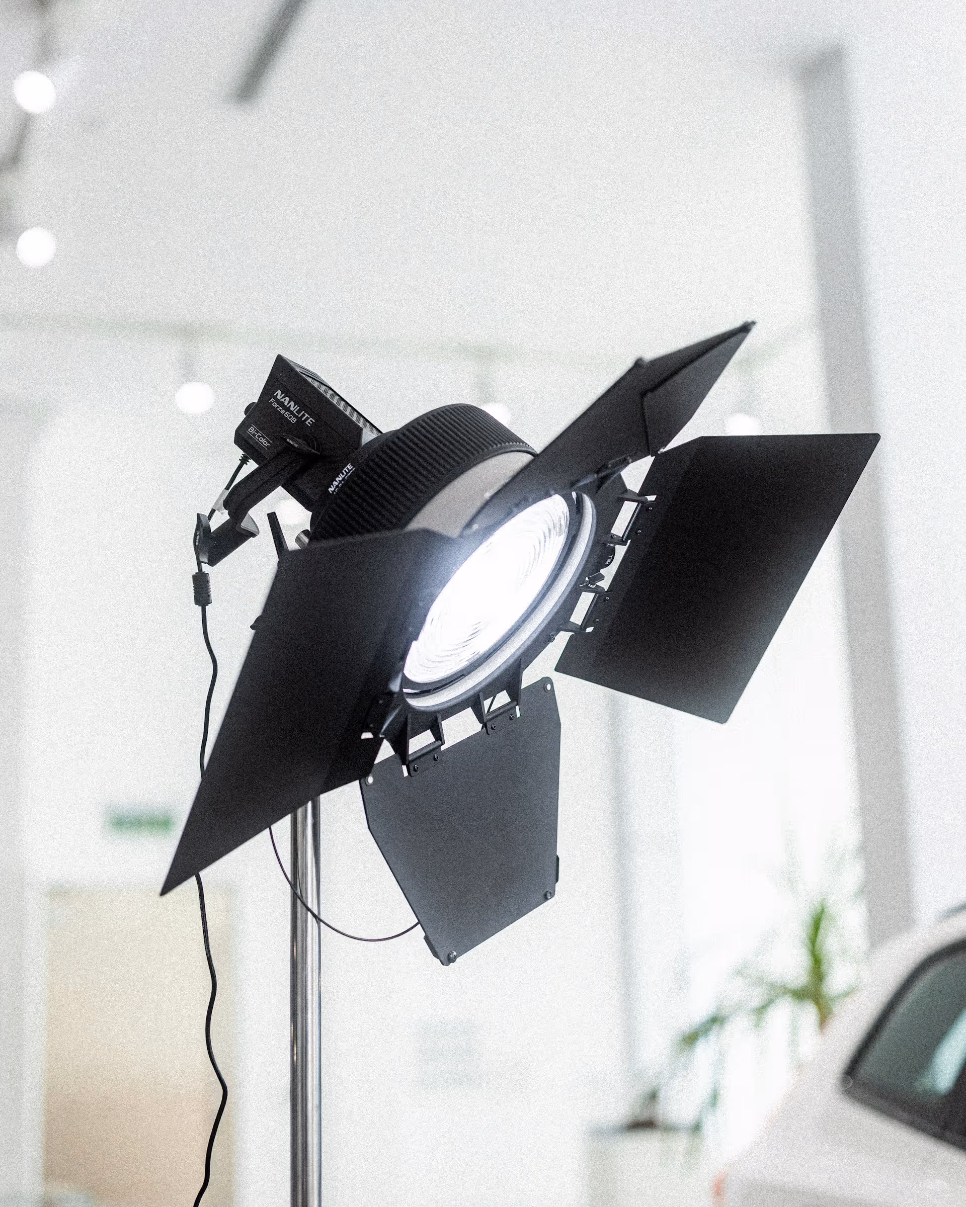 Studio spotlight with barn doors on a stand illuminating a bright white room.