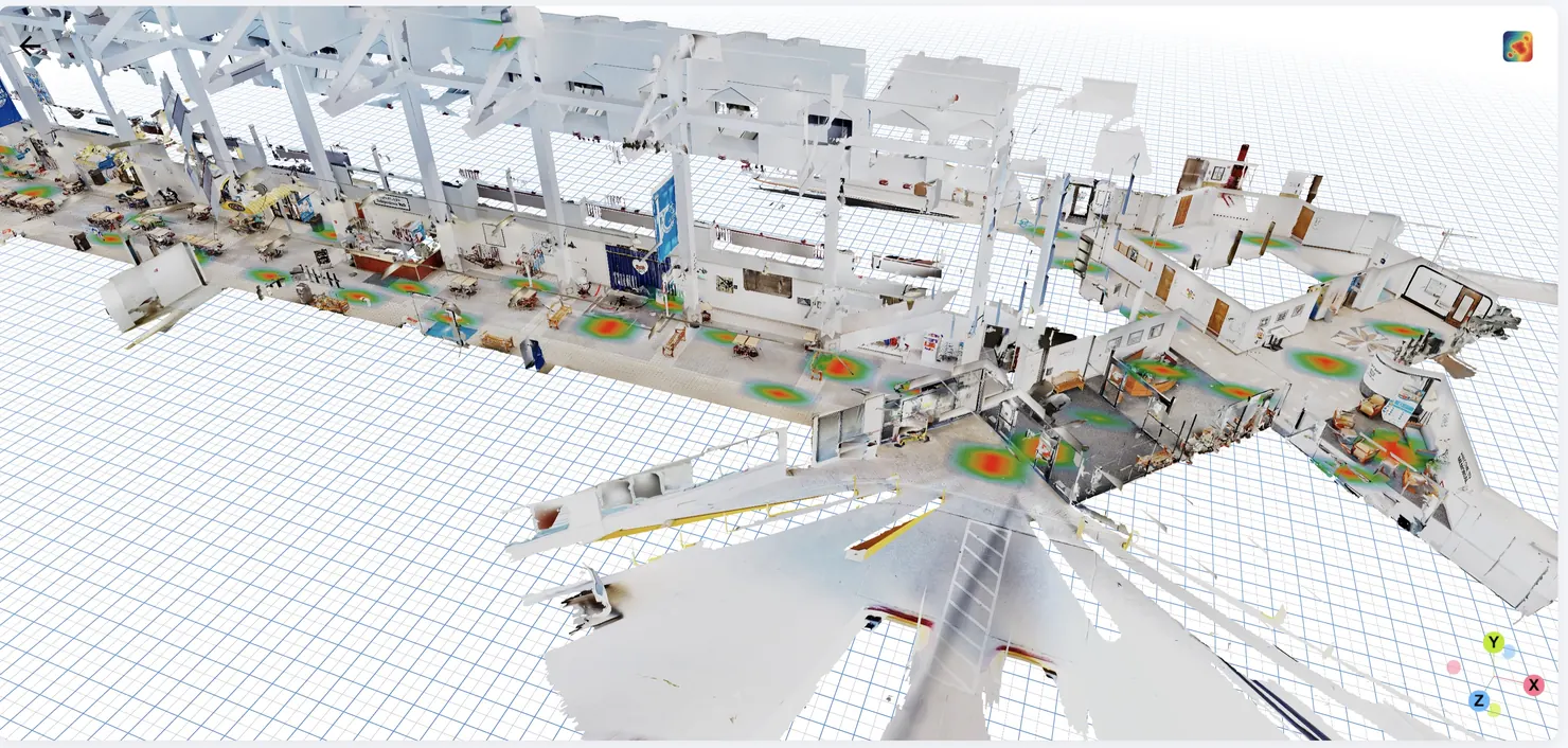 A 3D scan of a factory floor and its side rooms seen from above on a grid, with red and green heatmap blobs scattered across the floor marking where devices localized most often