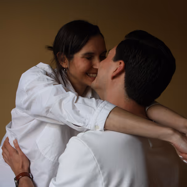 Een vrouw en man omhelzen elkaar en glimlachen met hun gezichten dicht bij elkaar.