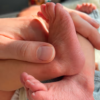 Hand die voorzichtig de kleine voet van een baby vasthoudt.