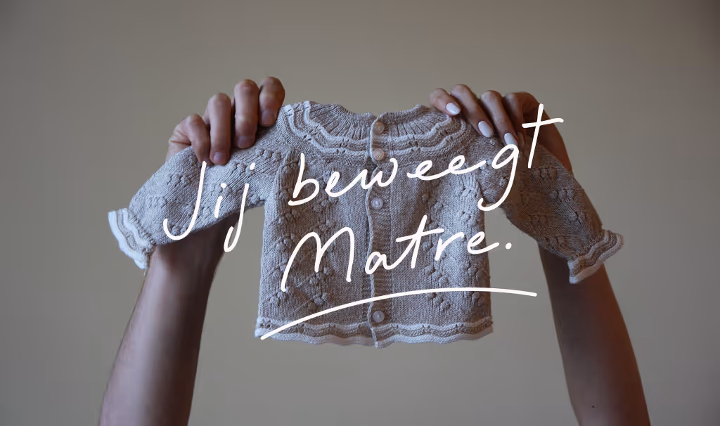Twee handen houden een gebreid babyvestje vast met de tekst 'Jij beweegt Matre.' erboven.
