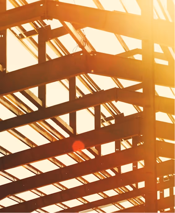 Sunlight shining through metal beams of a building framework.