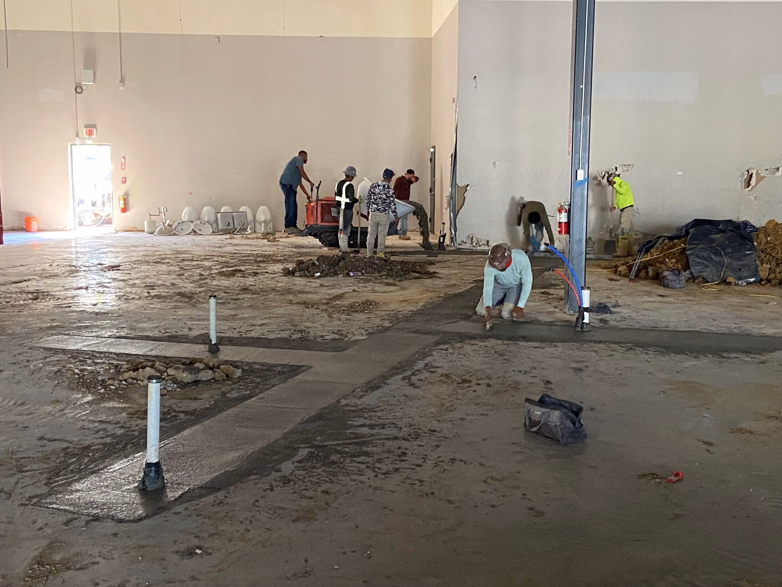 Two construction supervisors in white helmets inspecting a large building site with scaffolding and workers.