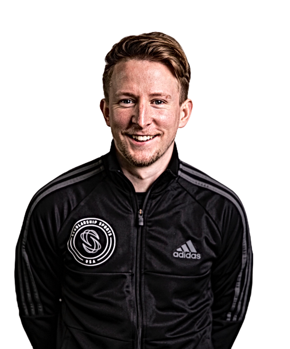 Smiling man with light brown hair wearing a black Adidas jacket with a circular USA sports logo on the left chest.