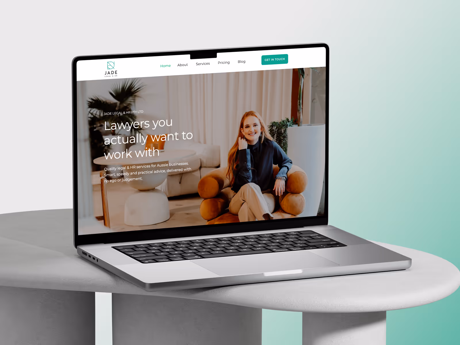 Laptop on a round table displaying Jade Legal & HR website with a smiling woman seated on a round orange chair.