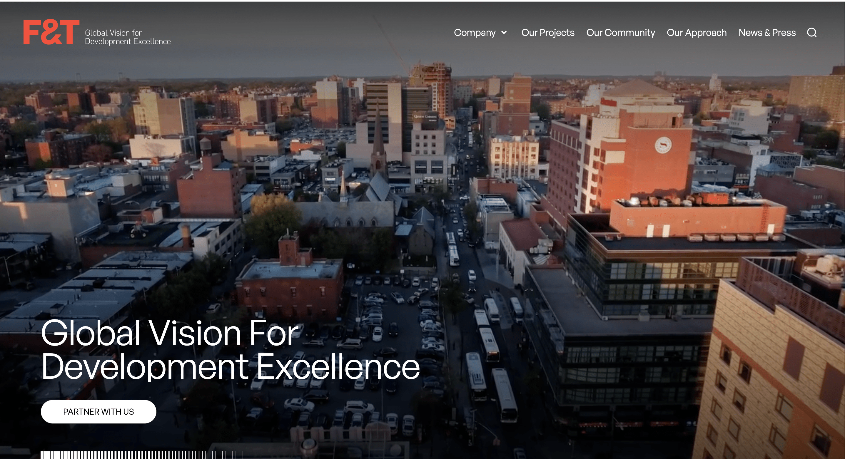 Aerial view of a cityscape with buildings, streets, and parked buses at sunset.