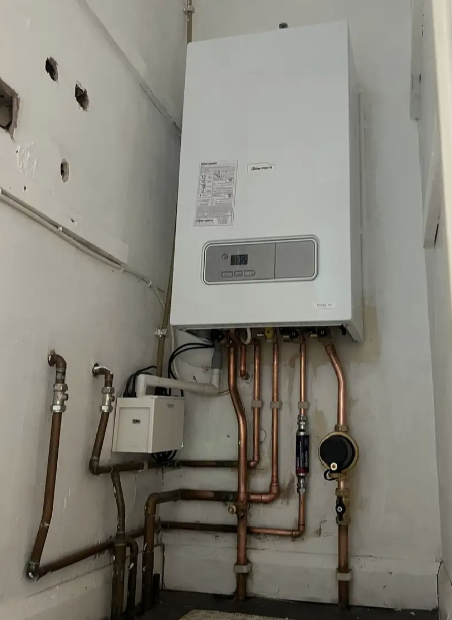 Wall-mounted Glow-worm boiler with copper piping and valves in a utility room.