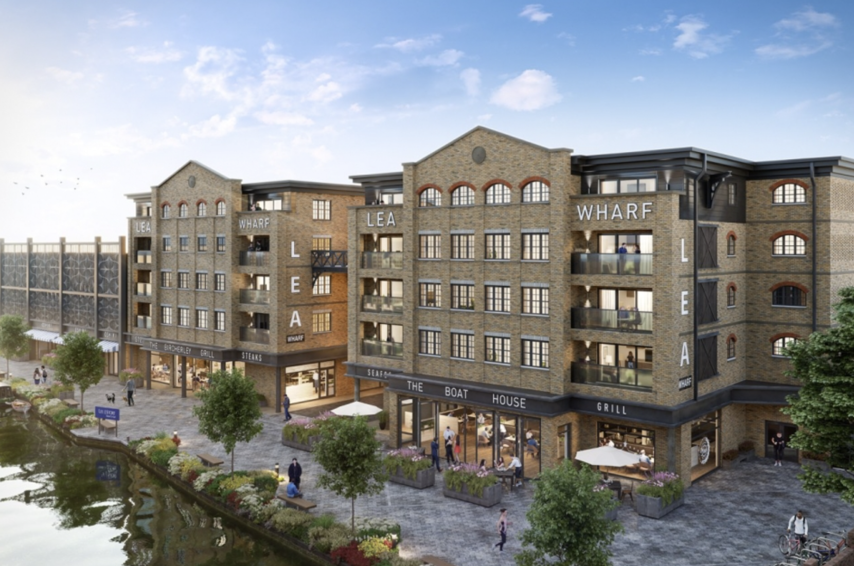 Modern brick building labeled Lea Wharf with ground-floor restaurants and outdoor seating by a waterfront promenade.