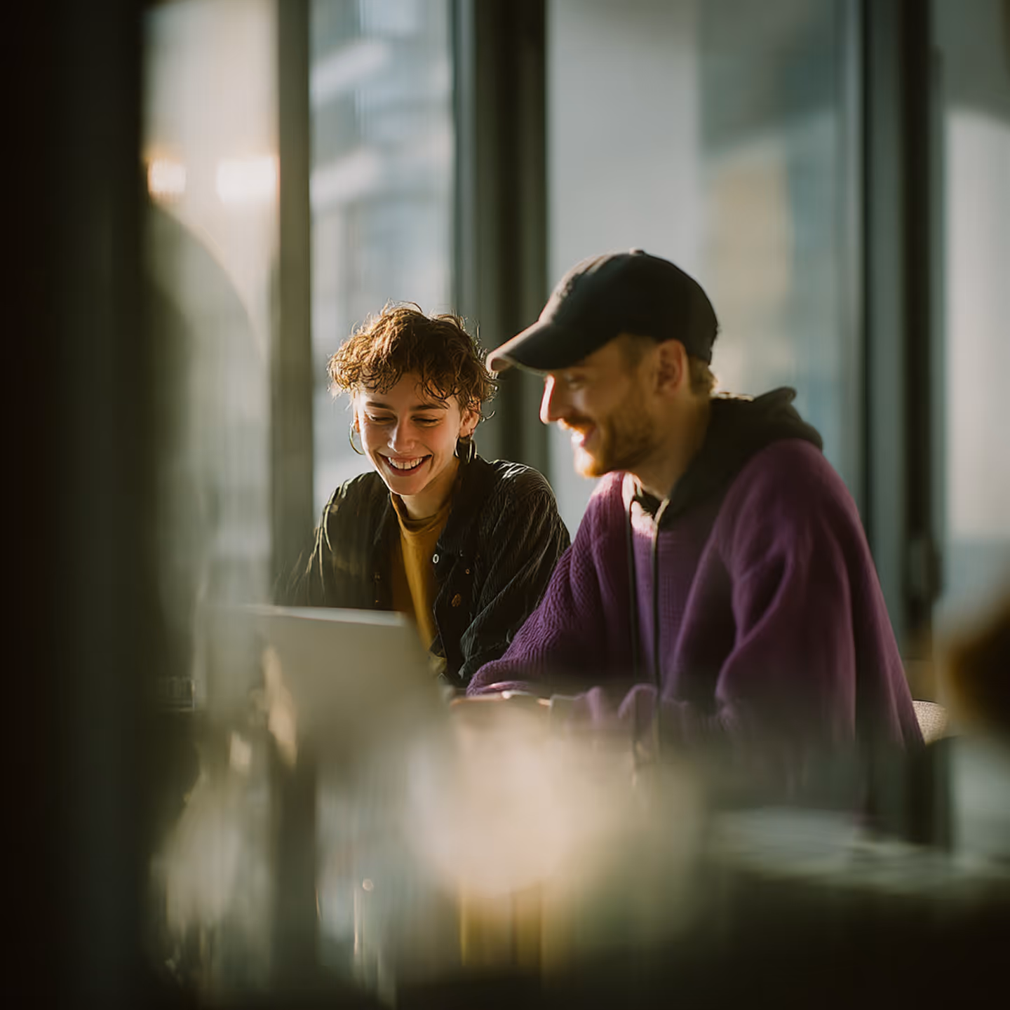 Photo - Two People Sitting Behind A Table Looking At A Laptop
