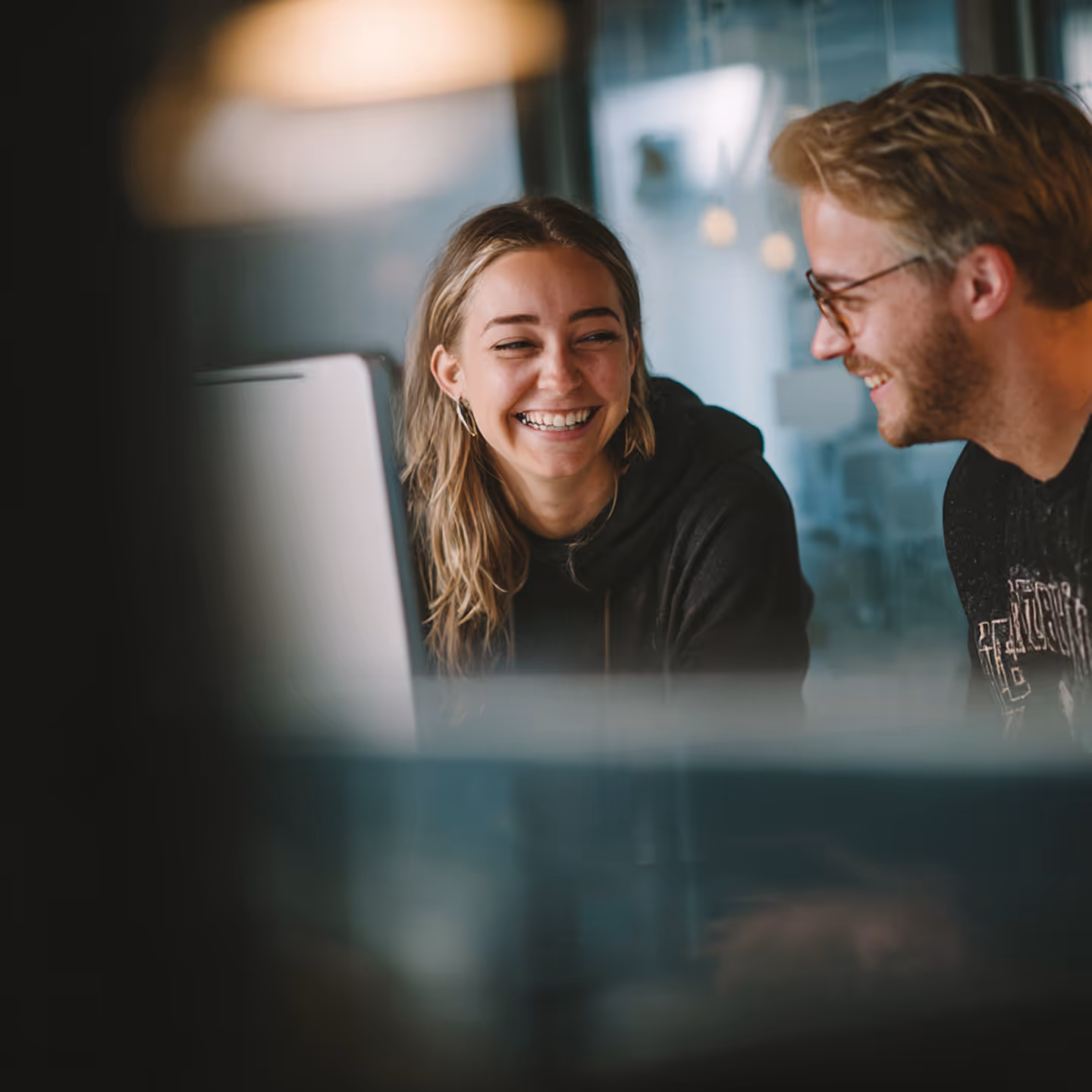 Photo - Two People Looking At Each Other Sitting Behind Computer