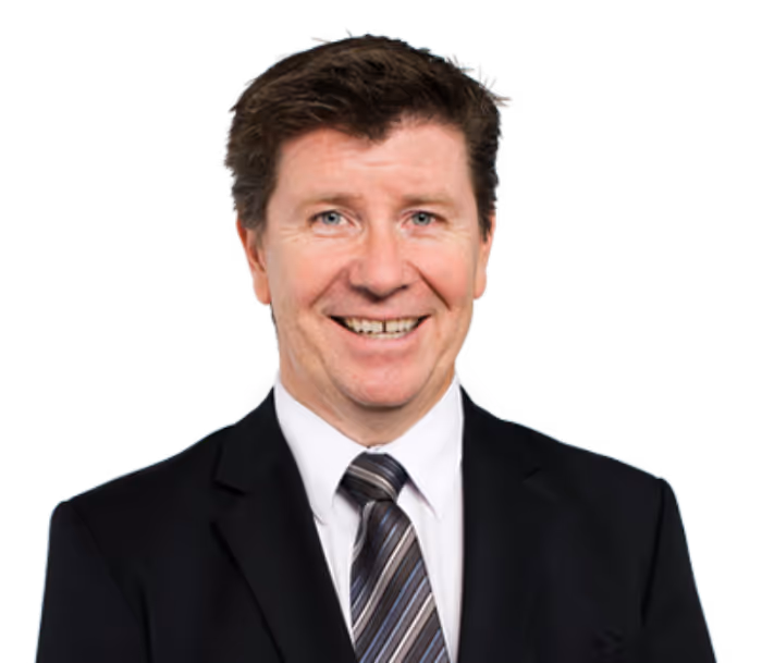 Smiling man with brown hair wearing a black suit, white shirt, and striped tie.