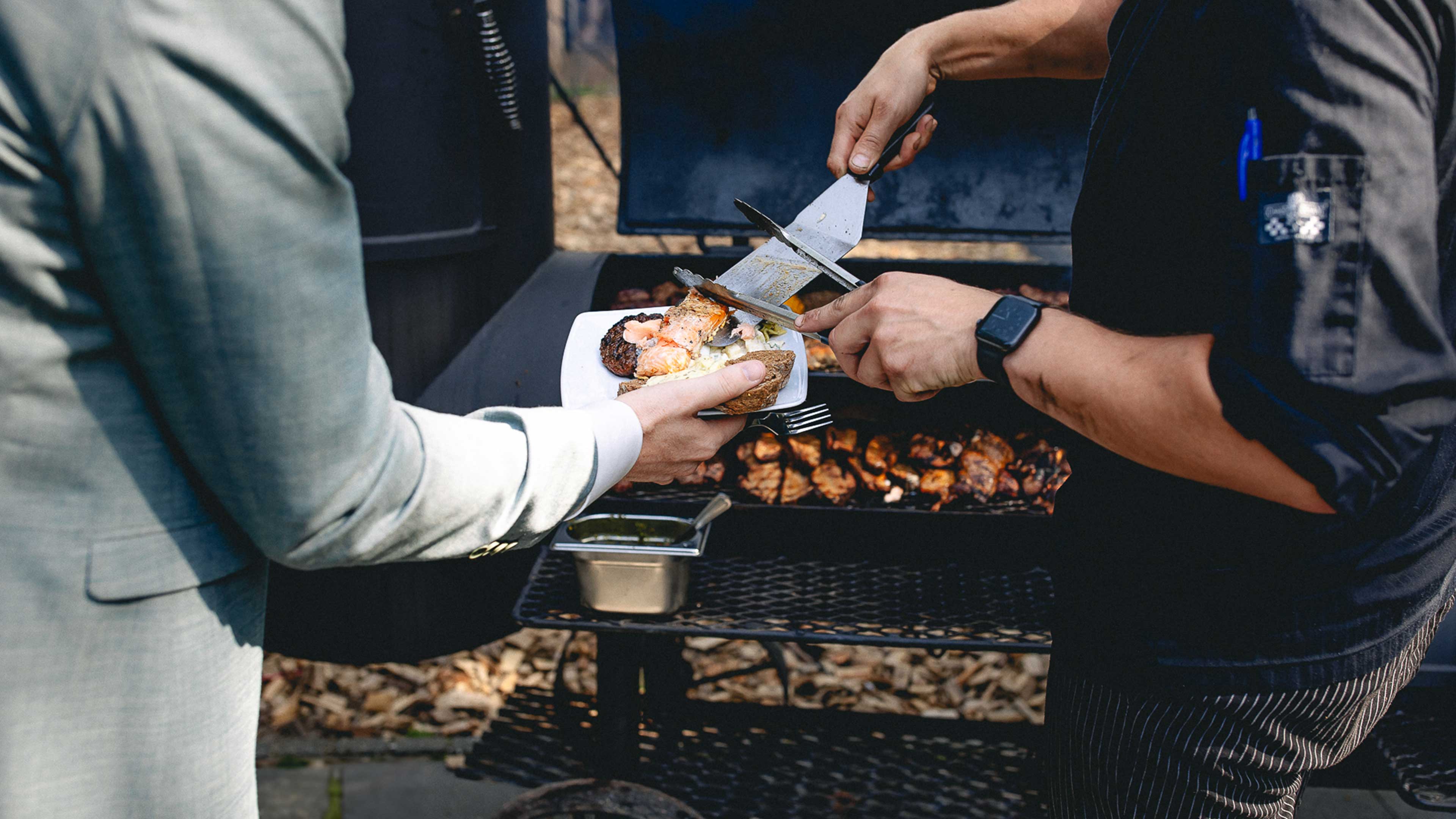 Chef van De Baron schept vlees van de barbecue op het bord van een gast