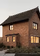 Two-story brick house with a sloped dark roof and illuminated windows at dusk.