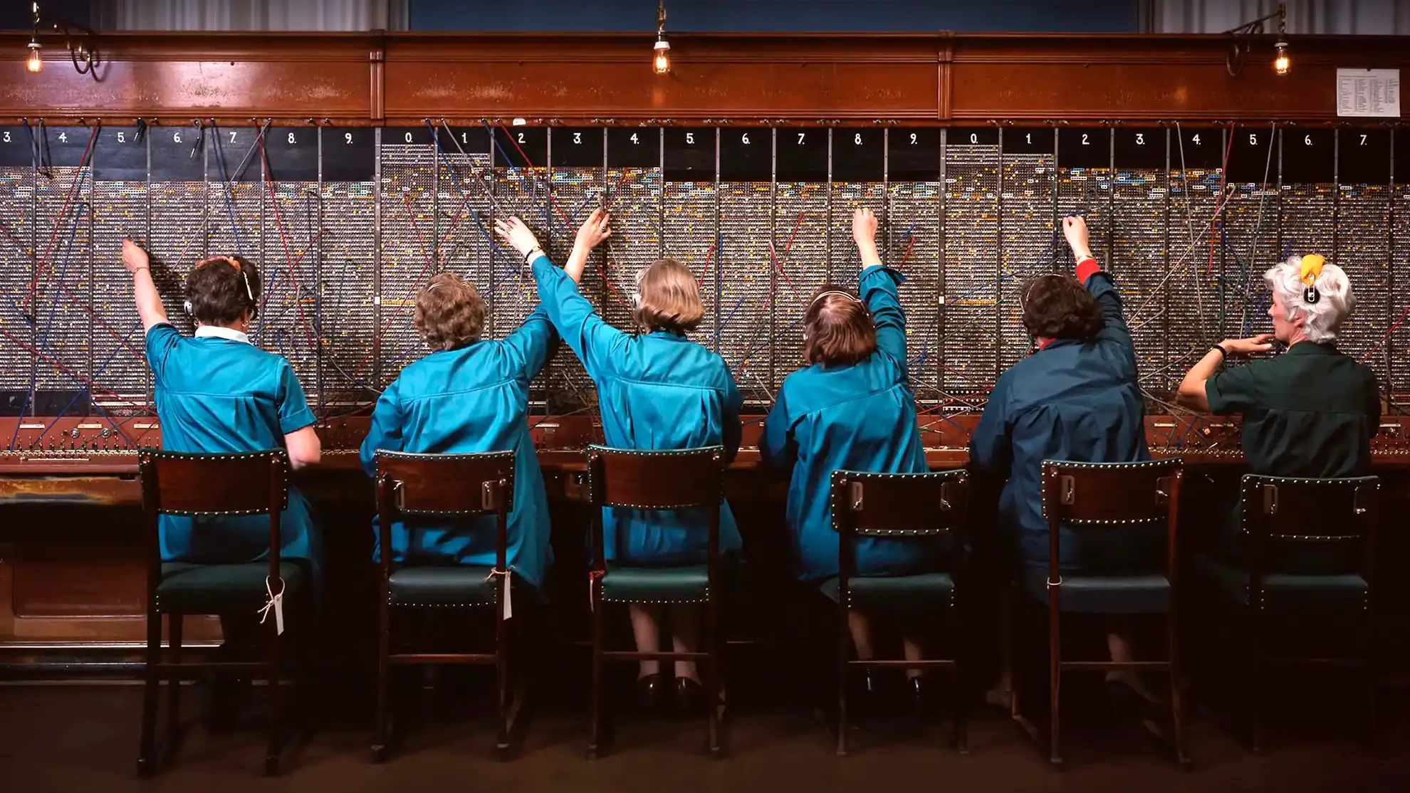Six women working at an old telephone exchange.