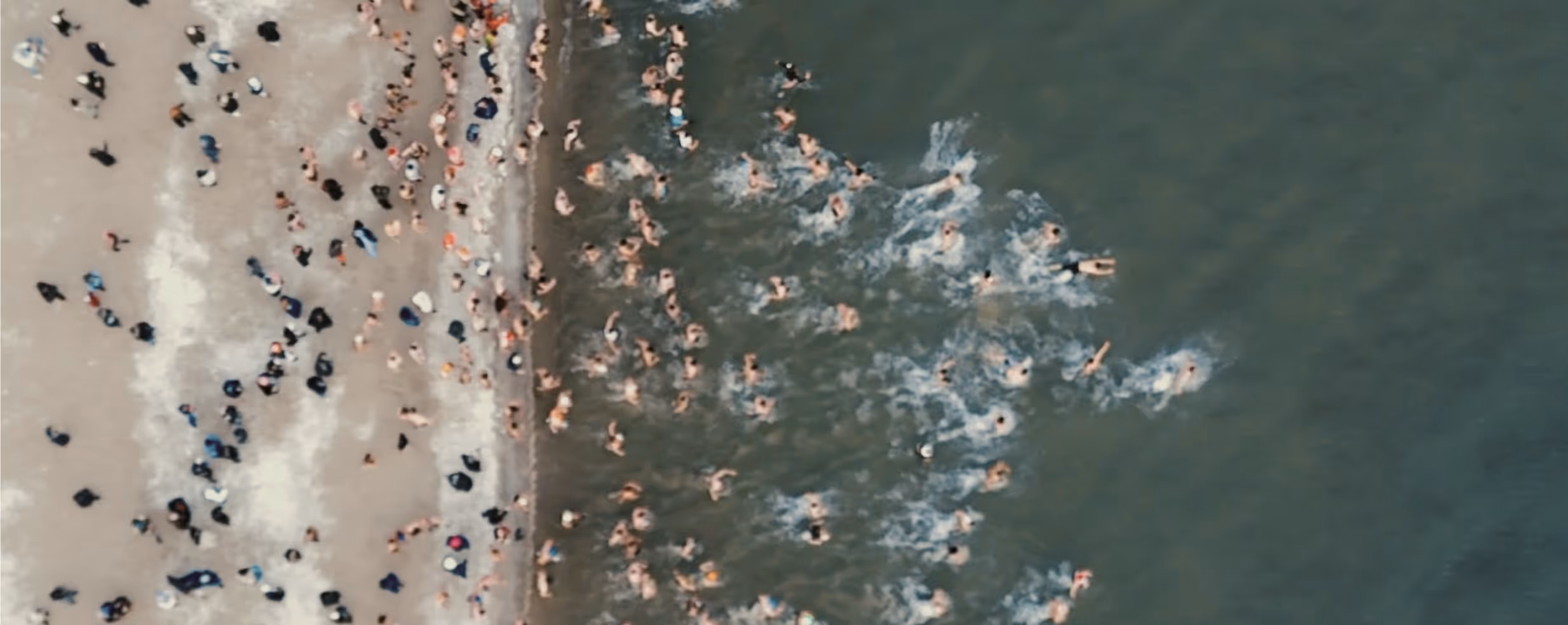 Group of nine people sitting and standing in a cozy wooden cabin living room with large windows and a lit fireplace.