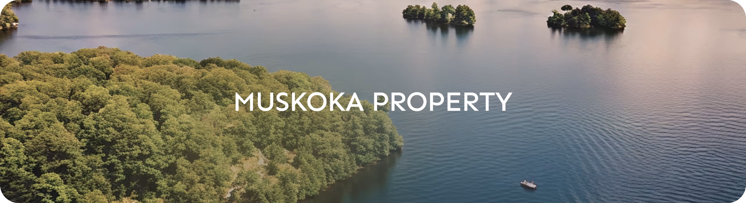 Group of people sitting and standing around a campfire outdoors at dusk, some holding warm mugs.