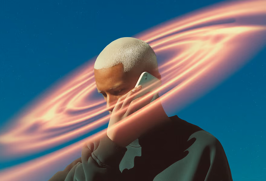 A person with a platinum blonde buzz cut, holding a phone, surrounded by glowing rings against a clear blue sky.