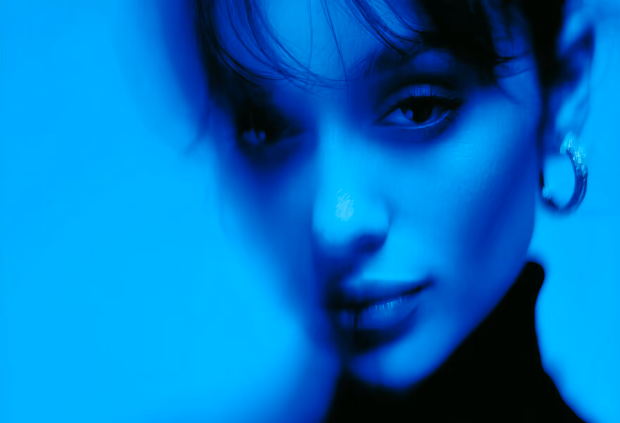 Stylized portrait with a blue overlay, featuring a person in a black turtleneck and soft focus for an artistic, dreamy effect.