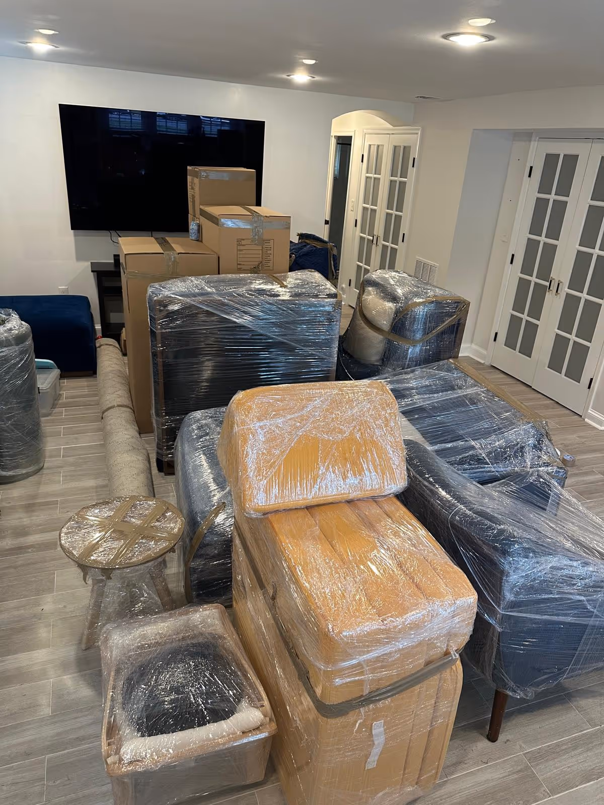 Living room with furniture and cardboard boxes wrapped in plastic wrap, ready for moving.