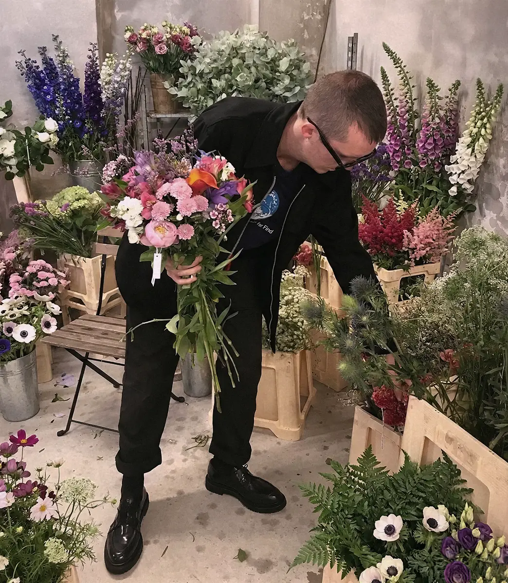 Guest holding a bouquet inside the PSEUDONYM Spring Summer 2020 floral installation during Copenhagen Fashion Week.