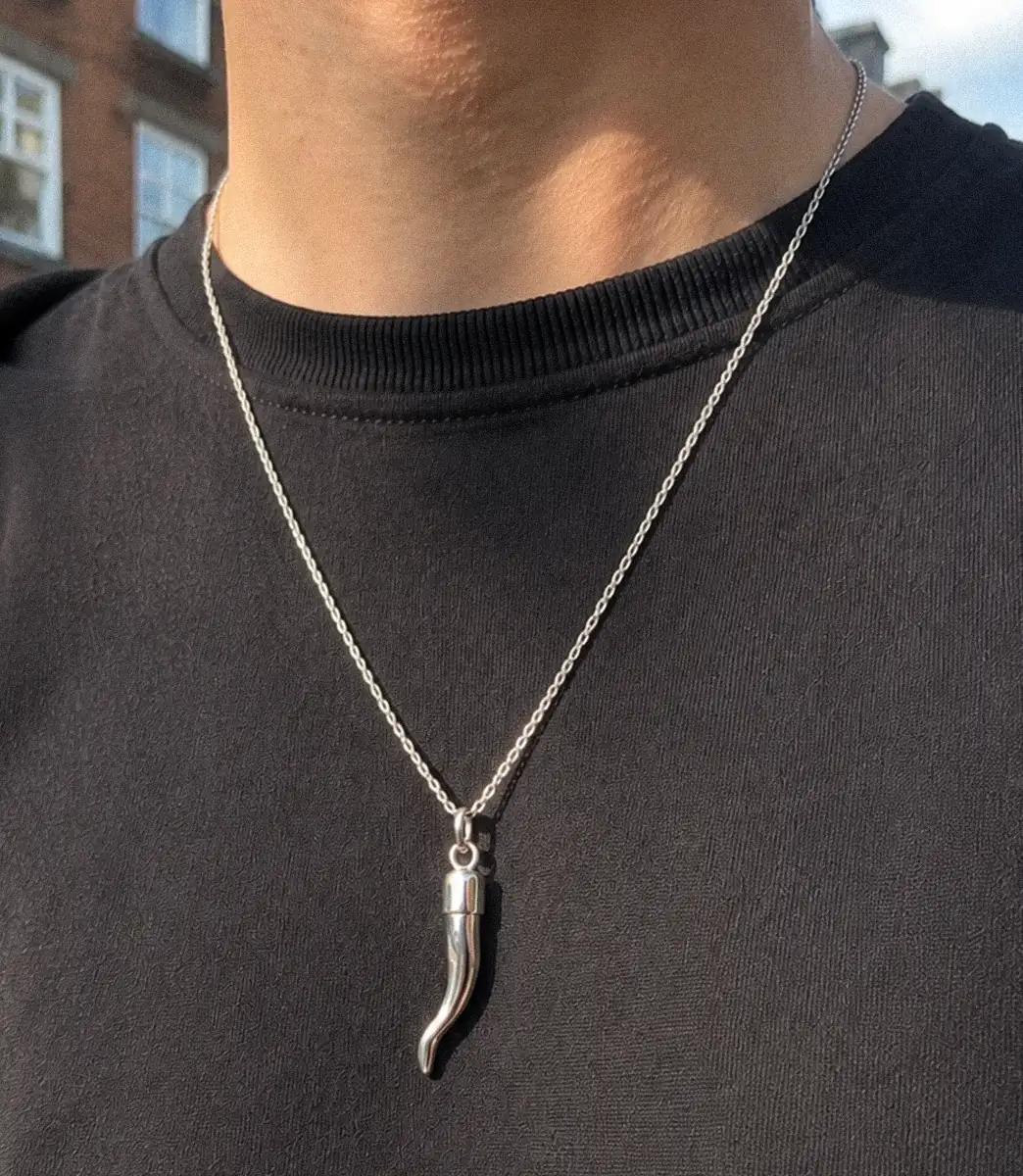 Silver cornicello charm necklace worn over a black t-shirt.