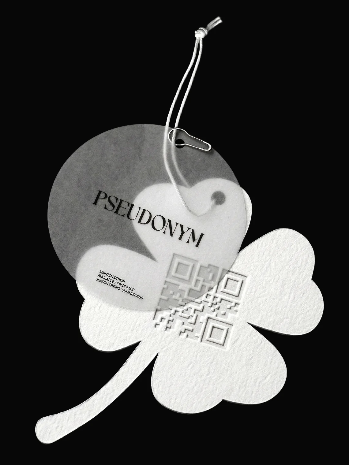 PSEUDONYM Spring Summer 2020 show production hangtag featuring layered translucent and embossed paper tags with clover-shaped detailing, string, pin, and QR-code texture on a black background.