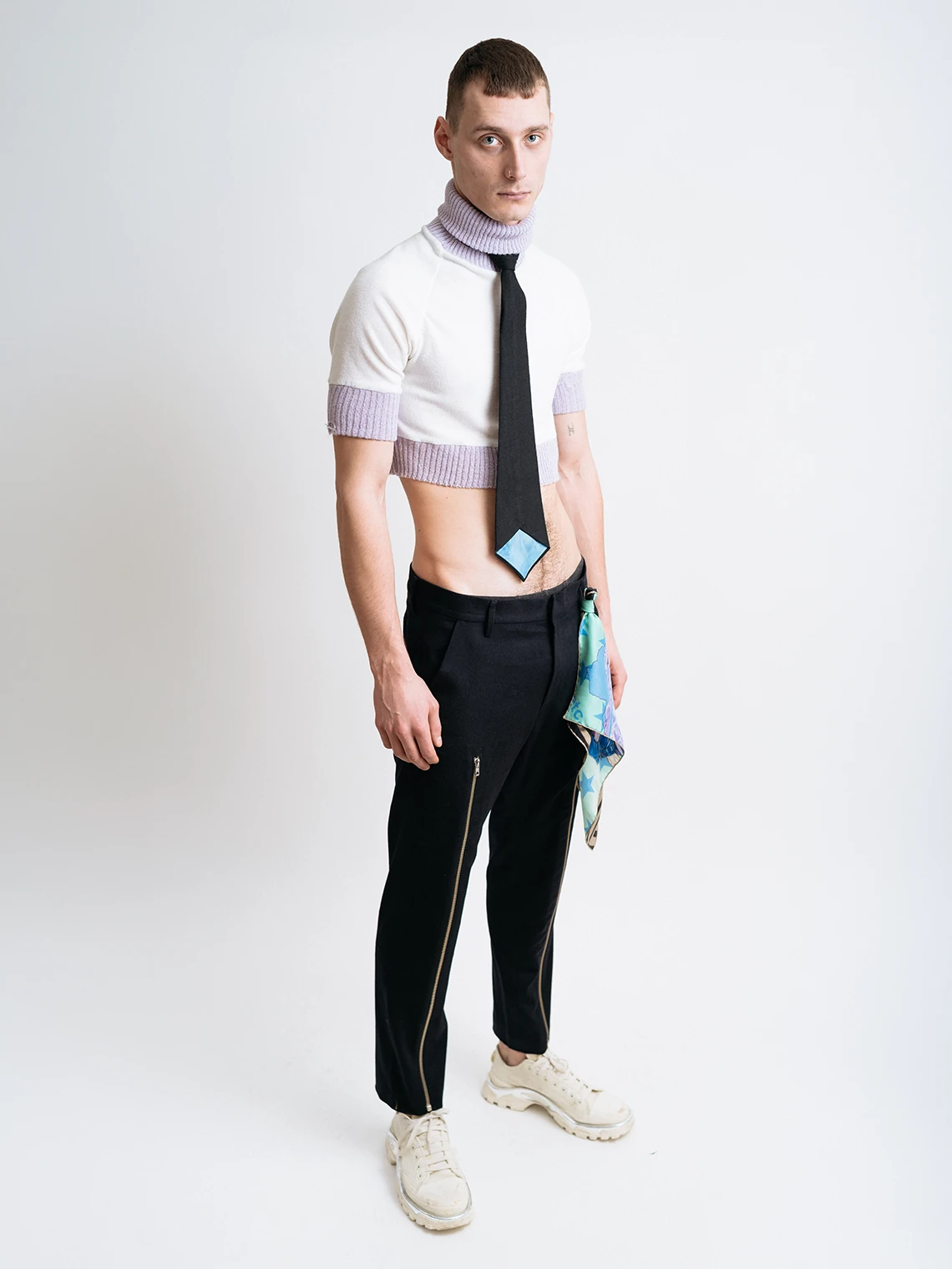 Model wearing a cropped knit top, black wool tie, slim black trousers, and silk scarf for PSEUDONYM Autumn Winter 2019.