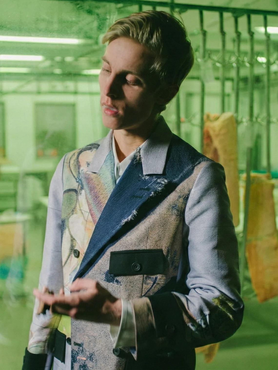 Model wearing a double-breasted jacquard racing jacket in a green-lit editorial setting for PSEUDONYM Autumn Winter 2019.