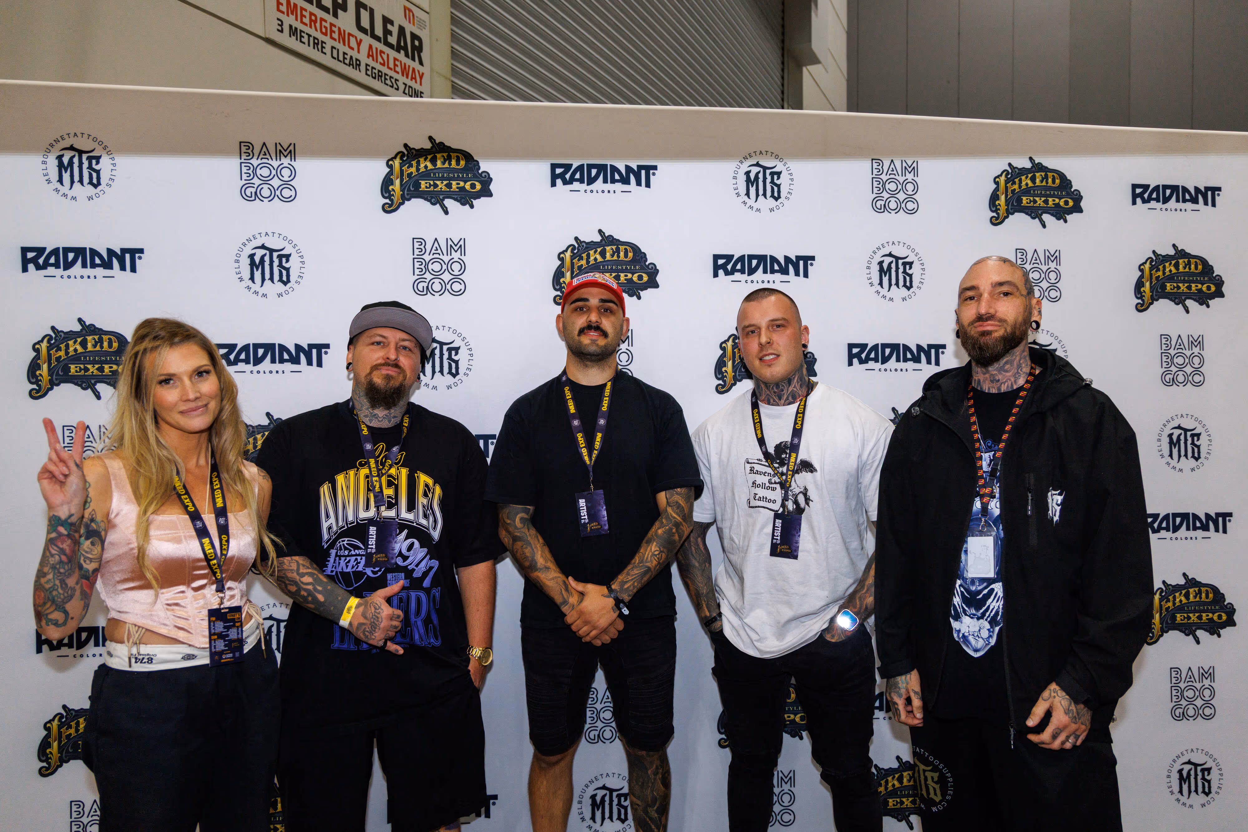 Five tattooed people posing in front of a backdrop at the Inked Lifestyle Expo.