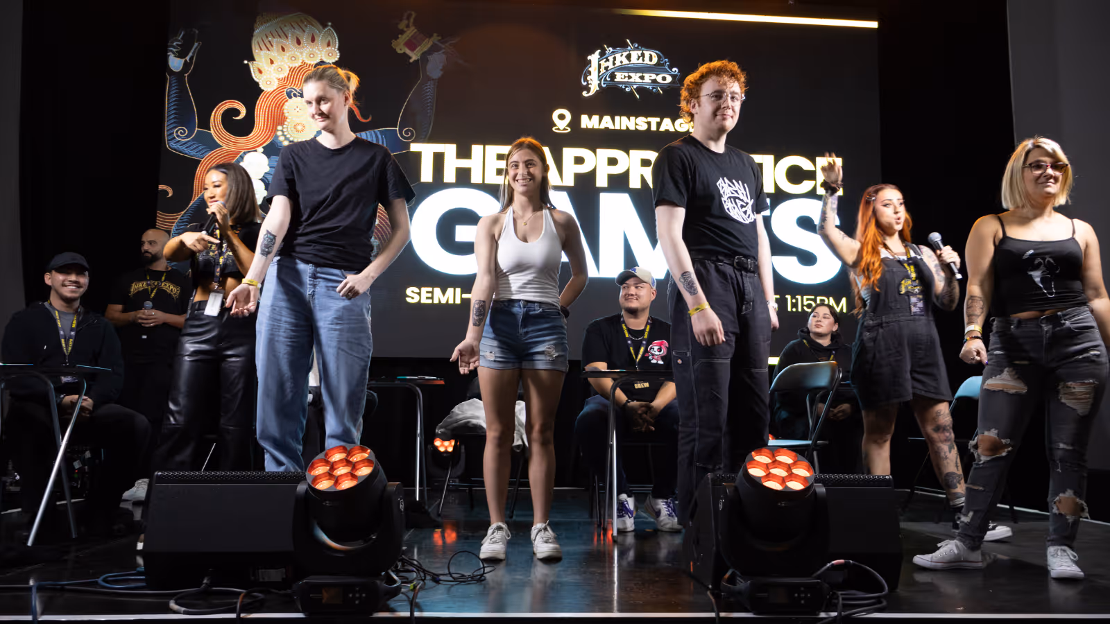 Group of young adults standing and holding hands on stage during a competition event called The Apprentice Games.