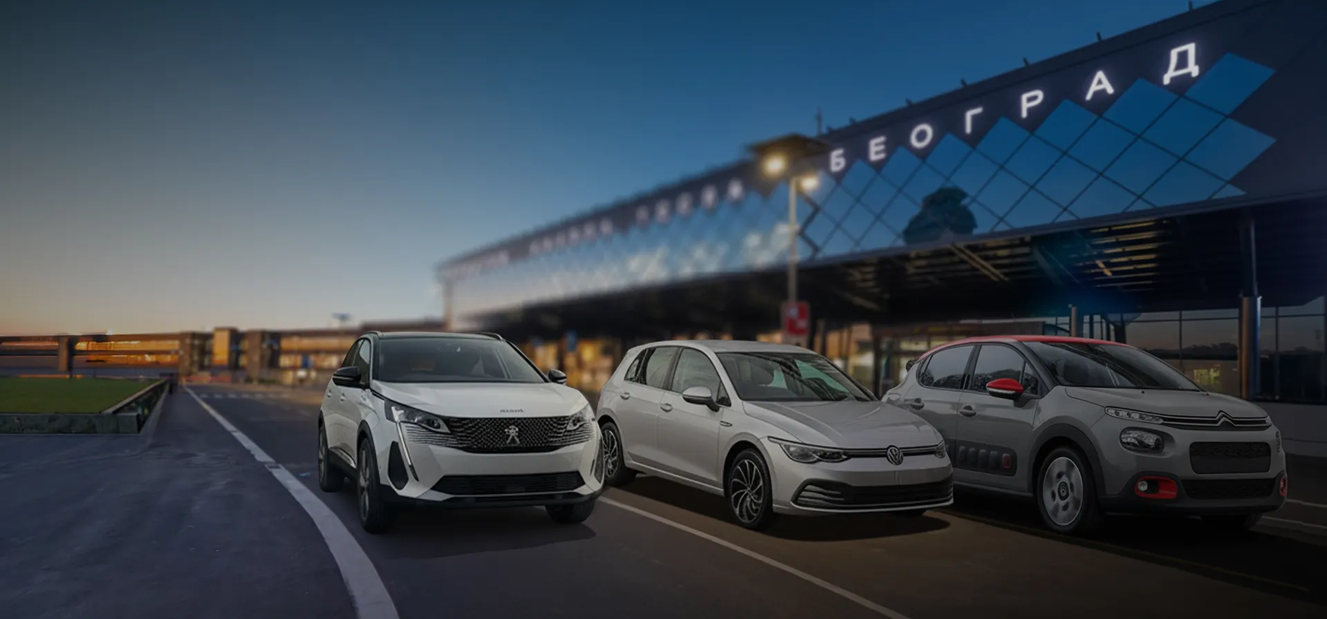 Three modern cars, a white Peugeot SUV, a silver Volkswagen hatchback, and a gray Citroën, parked in front of a building with illuminated Cyrillic signage at dusk.
