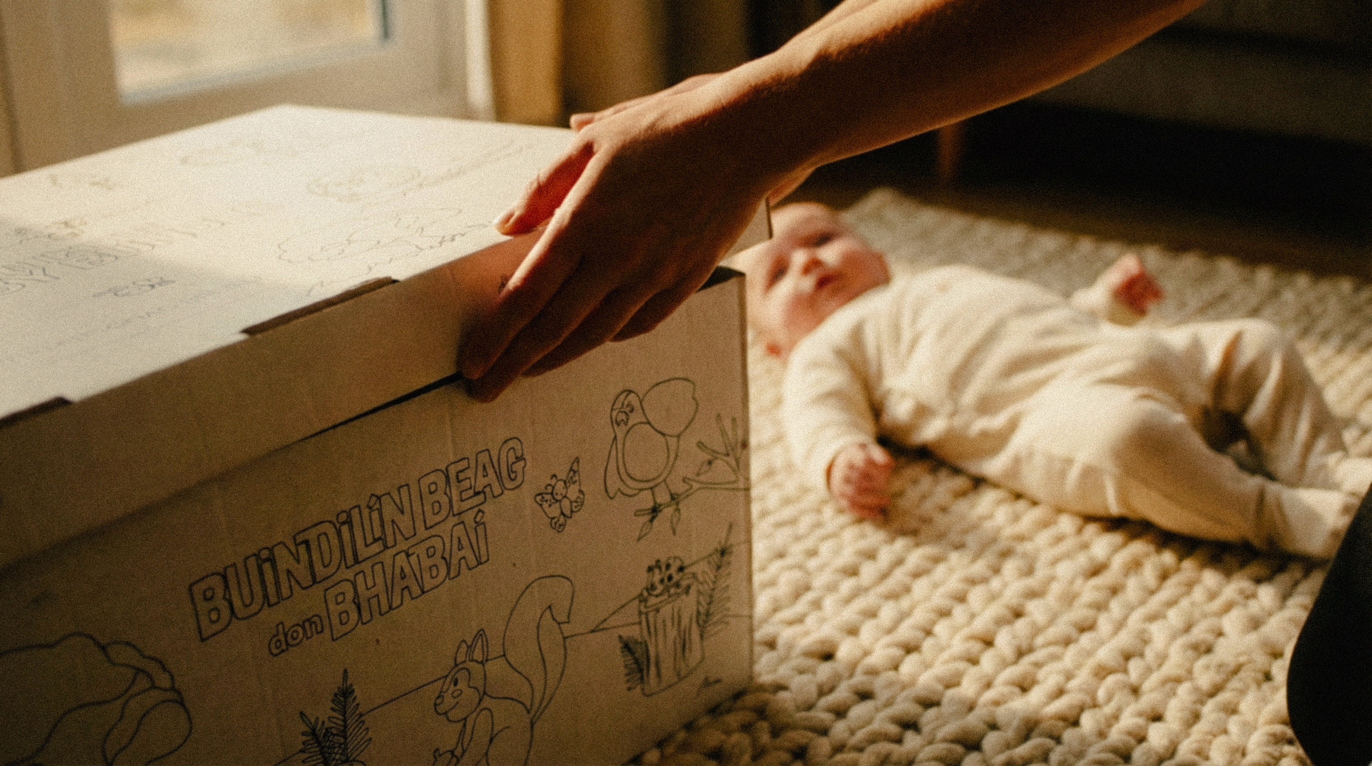 Two people lying on a patterned rug in a cozy room, looking at a laptop and writing in a notebook surrounded by plants and comfortable furniture.