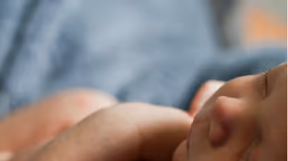 Close-up of a sleeping baby lying on a soft surface with a blurred background.