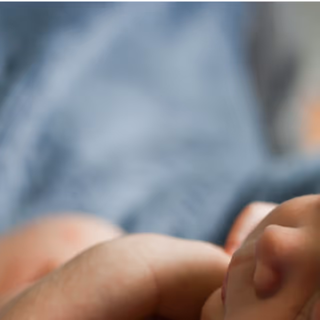 Close-up of a sleeping newborn baby wrapped in a blue blanket.