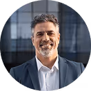 Lächelnder Mann im Anzug vor modernem Glasgebäude.