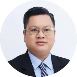 Smiling man with light skin and short hair wearing a black hoodie against a black background.