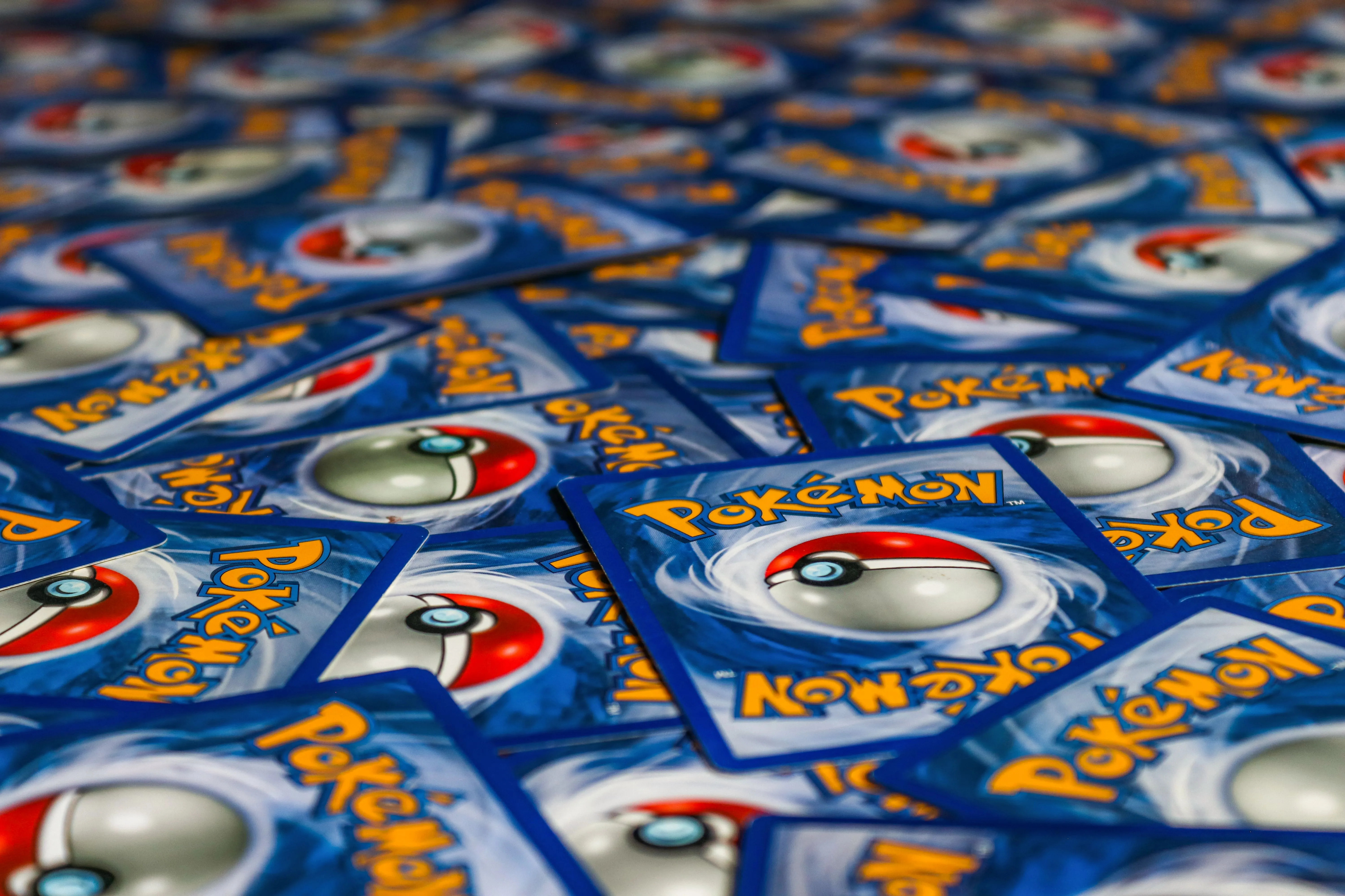 Plusieurs cartes Pokémon dos visible avec logo et Poké Ball rouges et blancs.
