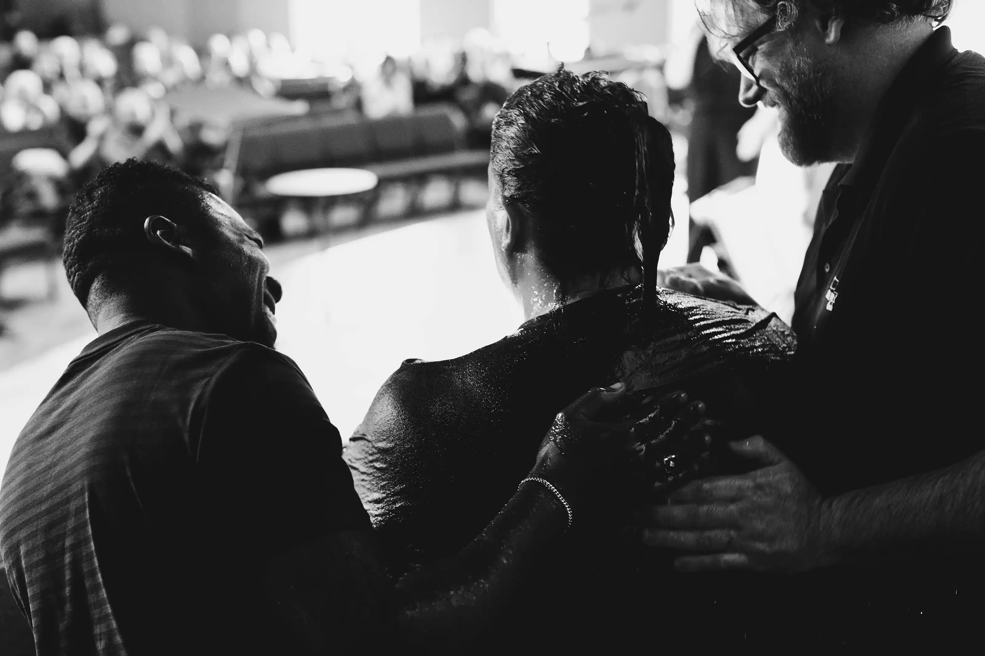 Two men smiling and rejoicing with a woman who was just baptized.