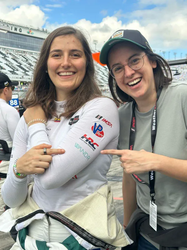 Two Wandr team members pointing to the Wandr logo on a racing suit