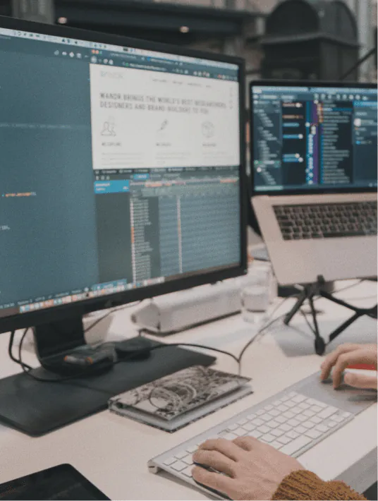 Side-by-side comparison of web design and web development workflows, showing a designer working on a visual mockup in Figma alongside a developer writing code in a text editor.