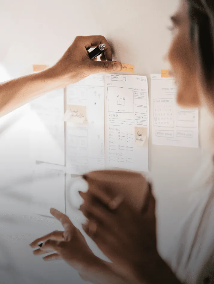 UX designer and product manager collaborating on a research plan with sticky notes, user journey maps, and data charts spread across a work table