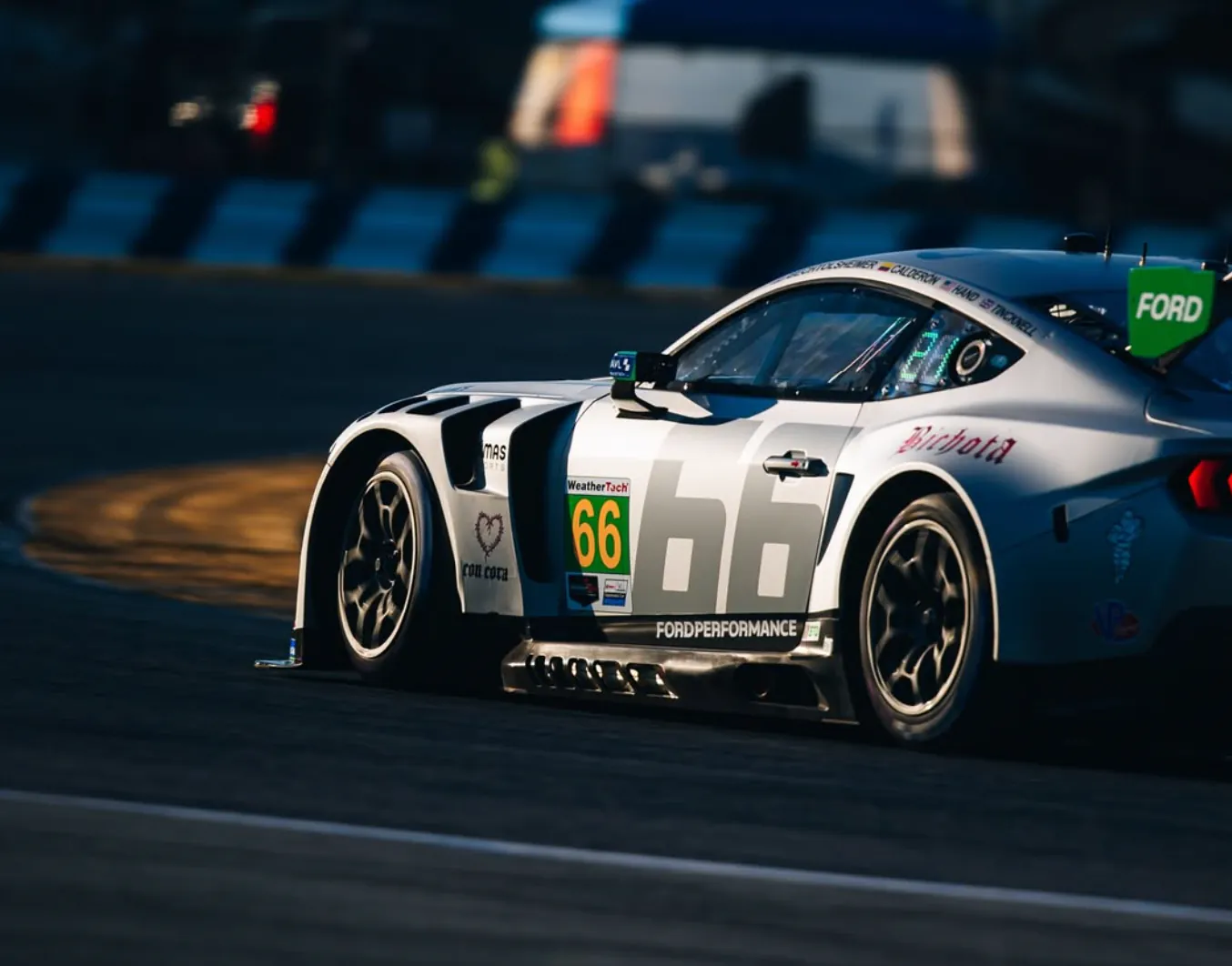 Race car on track at night, illustrating team communication and strategy in motorsports