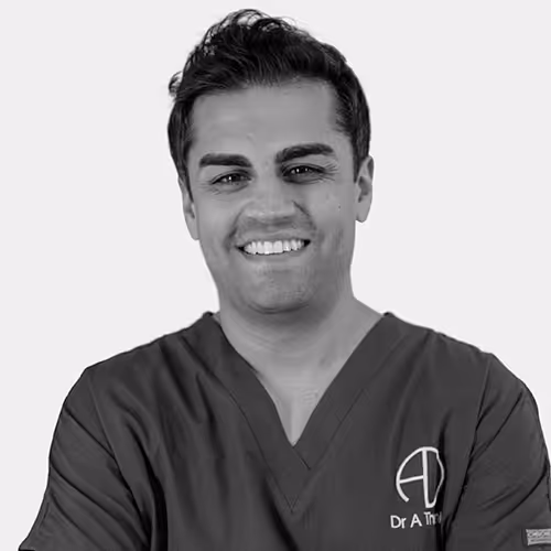 Smiling man wearing medical scrubs with logo and text on the chest.